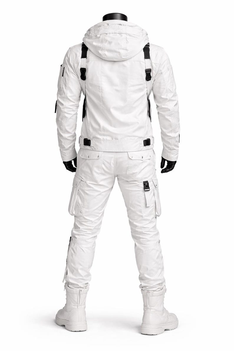 Pu&ograve; includere: Tuta da neve bianca con giacca con cappuccio e pantaloni abbinati. La giacca ha cinghie e fibbie nere, con tasche sulle maniche e sul petto. I pantaloni hanno tasche cargo e fibbie. L'outfit include stivali bianchi e guanti neri.