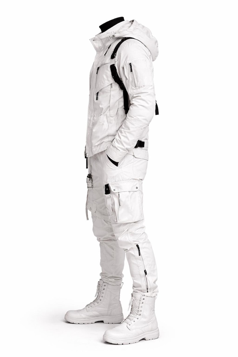 Pu&ograve; includere: Completo invernale bianco con giacca con cappuccio con tasche e cinghie nere, abbinato a pantaloni cargo e stivali bianchi. La giacca ha una chiusura a zip e i pantaloni hanno cerniere alle caviglie. Progettato per il clima freddo.