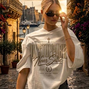 May include: An off-white short-sleeve t-shirt featuring the text "UNSTOPPABLE" in large block letters and "Never Settle" in script, along with a crown icon, the words "RELENTLESS AMBITION," and a circular emblem with the letters "LS" and "EST. MMXX."