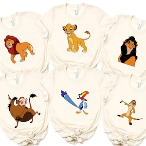 May include: Six cream-colored t-shirts featuring characters from The Lion King. The designs include Simba, Scar, Timon, Pumbaa, Zazu, and Mufasa. Each shirt has a different character illustration.