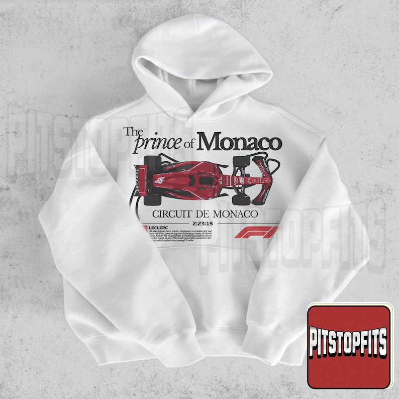May include: White hoodie featuring a red race car graphic with the text "The Prince of Monaco" and "Circuit de Monaco 2:23:15". The design includes the F1 logo and a small text box with the name "Leclerc".