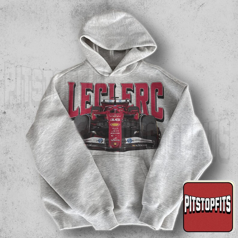 May include: A light gray hooded sweatshirt featuring a red and black race car graphic with the name "LECLERC" in red block letters. The sweatshirt has a kangaroo pocket and a drawstring hood. The Pitstopfits logo is in the lower right corner.