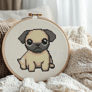 May include: A cross-stitch embroidery hoop with a beige background and a cartoon pug with brown eyes and a black nose. The pug is sitting with its legs crossed and its tail curled.