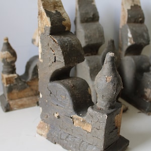 May include: A collection of weathered, antique wooden architectural elements. The pieces are painted in a distressed gray with exposed wood and peeling paint. The decorative elements have a unique, aged appearance.