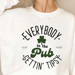 May include: White sweatshirt with a green and black graphic. The graphic reads "EVERYBODY in the Pub GETTIN' TIPSY" with a shamrock in the center. The words "Saint" and "Paddy" are also included.