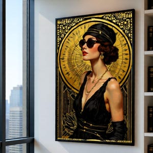 May include: A framed art print featuring a woman in a black dress and sunglasses, set against a gold Art Deco background. The artwork is displayed on a white wall near a window with a city view and a bookshelf.