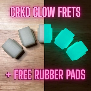May include: The image shows four rectangular CRKD Glow Frets, two of which glow bright teal. The text "CRKD GLOW FRETS" and "+ FREE RUBBER PADS" are displayed in pink neon. The frets are shown on a wooden surface.