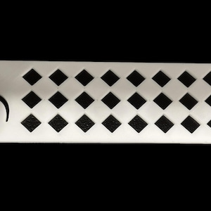 Puede incluir: Marcapáginas de plástico blanco con forma de nota musical y un patrón de diamantes negros.