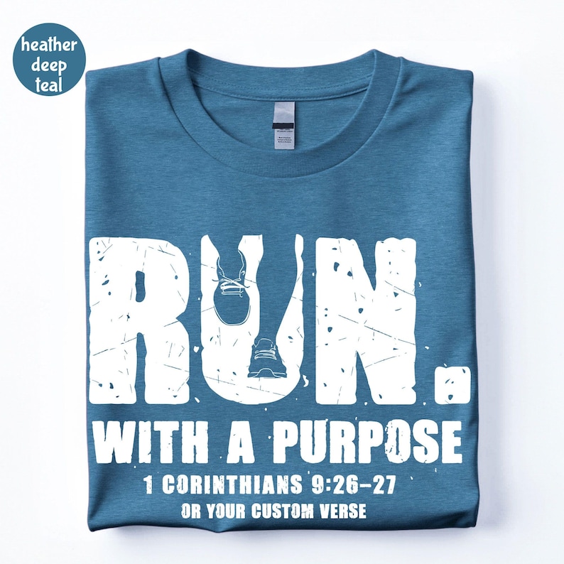 May include: A heather deep teal t-shirt featuring white distressed text that reads RUN. WITH A PURPOSE 1 CORINTHIANS 9:26-27 OR YOUR CUSTOM VERSE. The letter U in RUN incorporates a graphic of a running shoe and a leg in motion.