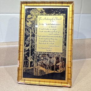 May include: A framed print with a gold-colored frame. The print features a black and gold illustration of trees and a poem titled "The Making of a Friend". The poem is written in a decorative font.