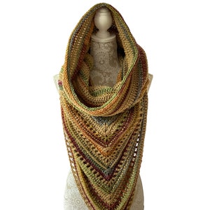 May include: A crocheted shawl in shades of brown, green, and red. The shawl is draped over a mannequin and has a hood.