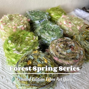 May include: A collection of green, yellow, and pink fiber art yarn balls. The yarn is fluffy and textured, with a variety of shades and colors. The text "Forest Spring Series" and "Limited Edition Fibre Art Yarn" is visible.