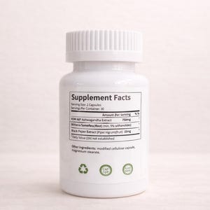 May include: A white supplement bottle with a white cap. The label includes the text "Supplement Facts" and ingredient information, including Ashwagandha Extract and Black Pepper Extract. The bottle has green plant-based symbols.