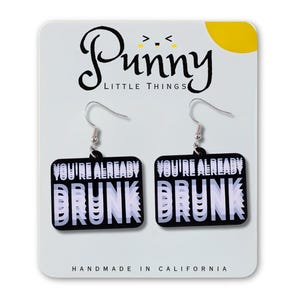 Könnte beinhalten: Schwarz-weiße Ohrringe mit dem Text "YOU'RE ALREADY DRUNK" in fetter Schrift. Die Ohrringe befinden sich auf einer weißen Karte mit dem Logo "Punny Little Things" und dem Text "HANDMADE IN CALIFORNIA".