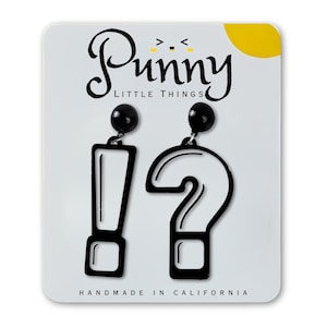May include: Black exclamation point and question mark earrings on a white card. The earrings are outlined in black and have a small black ball at the top. The card has the text "Punny Little Things" and "Handmade in California".