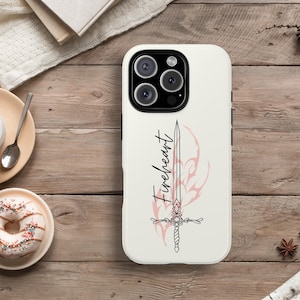 May include: A white phone case with a sword design and the word "Fireheart" in a script font. The sword is pink and black, with a decorative tribal design behind it. The case has a glossy finish.