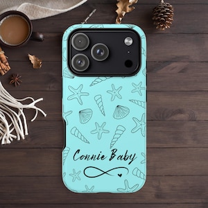 May include: A light blue phone case featuring a pattern of black seashells and starfish. The case has the text "Connie Baby" with an infinity symbol and a heart. The case is designed for a smartphone.