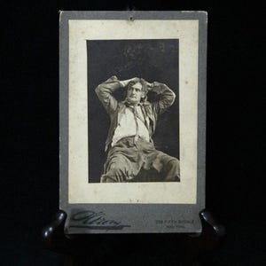 May include: Vintage black and white photograph of a man seated with his hands behind his head. The photograph is mounted on a gray card with the studio name "Wiren" and address "575 Fifth Avenue, New York" printed on the bottom.