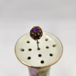 Broche de sombrero victoriano vintage de principios del siglo XX con bola de diamantes de imitación en color morado, rosa y dorado.