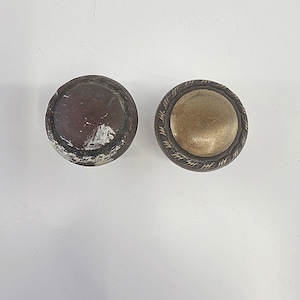 May include: A set of three ceramic mugs with a speckled, matte finish. The mugs are in shades of cream, light brown, and dark brown. Each mug has a simple, minimalist design and a rounded handle. The mugs are likely for coffee or tea.