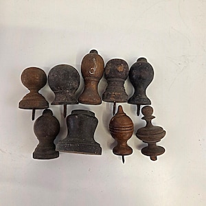 Puede incluir: Una colección de diez remates de madera antiguos en varias formas y tonos marrones. Cada remate tiene un tornillo que sobresale de la base. Los remates varían en tamaño y diseño, algunos con tapas redondeadas y otros con detalles más intrincados.