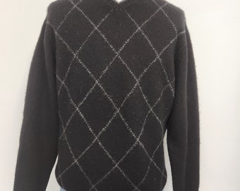May include: Black sweater with a diamond pattern in gray. The sweater has a v-neck and long sleeves.