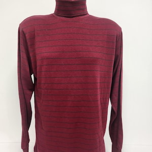 Könnte beinhalten: Ein langärmliger, burgunderfarbener Rollkragenpullover mit dünnen schwarzen horizontalen Streifen.