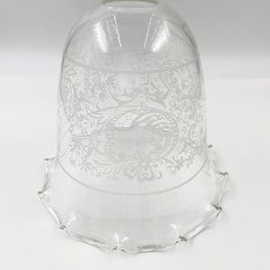 Könnte beinhalten: Transparenter Glasschirm mit geätzten Blumen- und Schriftrollenmustern. Der Lampenschirm hat einen ausgestellten, gewellten Rand. Das geätzte Design ist in der Mitte des Lampenschirms sichtbar.
