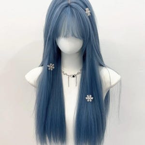 以下が含まれることがあります： 長いストレートヘアと前髪の青いウィッグ。マネキンの頭にセットされています。ウィッグには、3つのシルバーの雪の結晶ヘアクリップと、黒いペンダントが付いたシルバーのネックレスが付いています。