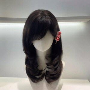 以下が含まれることがあります： 肩までの長さのレイヤーカットのダークブラウンのウィッグ。 赤と金のヘアクリップは、飴がけフルーツに似ており、側面に付いています。 ウィッグはマネキンの頭に展示されています。