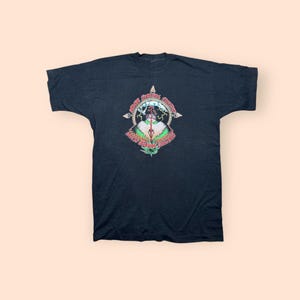 May include: Black t-shirt with a colorful graphic design. The graphic features text and an illustration of a figure with lightning bolts. The text reads "Angel Survival Company" and "Earthquake Relief".