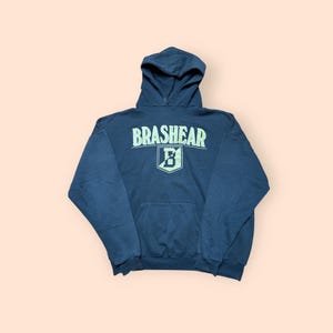 May include: A navy blue hooded sweatshirt with the word "BRASHEAR" in light green block letters across the chest. Below the word is a light green "B" inside a shield. The sweatshirt has a front pocket and a drawstring hood.