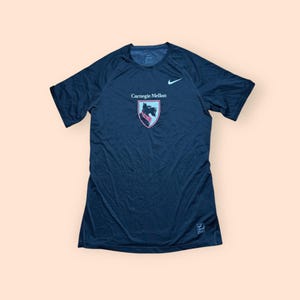 May include: A navy blue short-sleeve athletic shirt with the Carnegie Mellon logo and a Nike swoosh. The logo is a shield with a black dog and the words "Carnegie Mellon" in white.