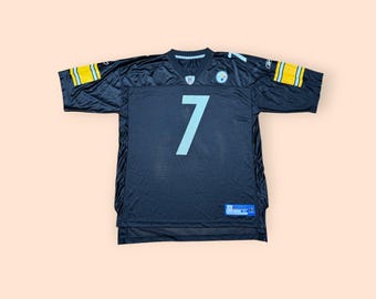 May include: A black short-sleeved jersey featuring the number 7 in white on the front. The sleeves have yellow and white stripes, and the Pittsburgh Steelers logo is on the upper left chest. A Reebok logo is on the right shoulder and sleeve.