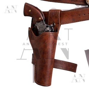 May include: A brown leather holster with a matching belt, holding a silver and brown revolver. The holster is designed to be worn on the hip. The image shows a close-up of the holster and gun, with the belt buckle visible.