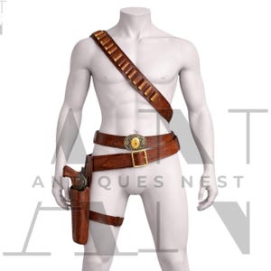 May include: A brown leather gun belt and shoulder strap with bullet loops, a holster, and a leg strap. The belt features a decorative gold-colored buckle. The mannequin is wearing a western-style outfit.