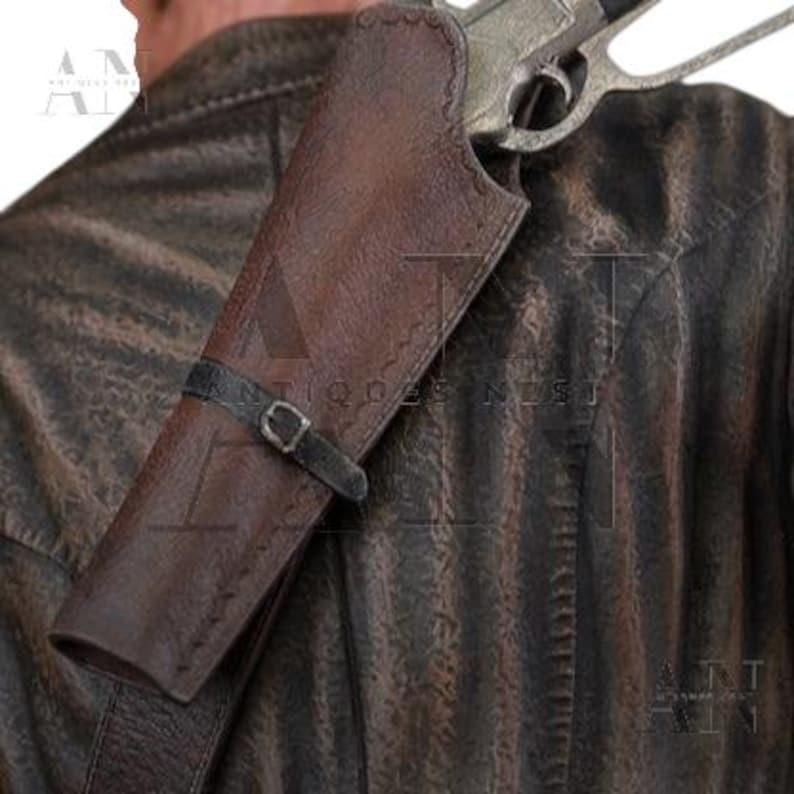 May include: A brown leather shoulder holster with a black strap and buckle, holding a silver handgun. The holster is worn over a brown leather jacket, suggesting a Western or vintage theme.