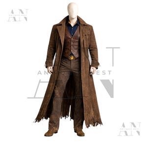May include: A brown suede duster coat, vest, and pants ensemble. The long coat has a distressed hem. The vest is leather, and the pants are a matching brown. A gold buckle belt and a blue shirt complete the outfit. The mannequin is standing on a white background.