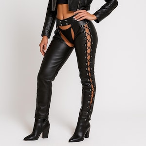 May include: Black leather pants with a lace-up design on the outer legs. The pants have a high waist and are paired with black heeled boots. A black leather jacket is also visible.