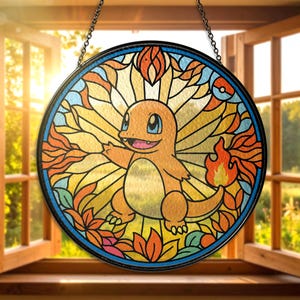 May include: Round stained glass window featuring a Charmander design. The artwork showcases an orange Charmander with a flame tail, surrounded by colorful floral and geometric patterns. The window is framed in black and hangs from a chain.