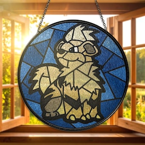 May include: A round stained glass window featuring a cartoon animal design. The artwork uses shades of blue, tan, and brown, with a black border and chain for hanging. The window is displayed in front of an open window.