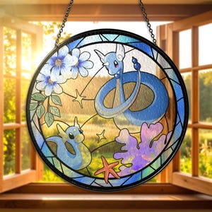 Può includere: Vetrata rotonda raffigurante due creature serpentine blu, fiori e una stella marina. L'opera d'arte è ambientata su uno sfondo di una scena esterna soleggiata. Il vetro è incorniciato in nero e appeso a una catena.