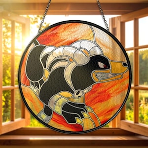 May include: Circular stained glass artwork depicting a cartoon character in black and yellow, with a red eye and sharp teeth. The background is a blend of orange and yellow colours, framed in black metal and suspended by a chain. The artwork is displayed in front of an open window.