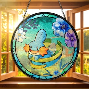 May include: Round stained glass window featuring a blue cartoon character with orange accents, surrounded by blue, white, and purple flowers. The window is framed in black and hangs from a chain.