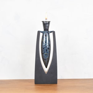 May include: A black ceramic candle holder with a blue and white patterned design. The candle holder is shaped like a vase and has a small opening at the top for a candle.