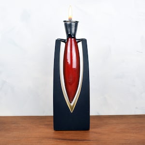 May include: A red ceramic candle holder with a black metal base and a flame on top.