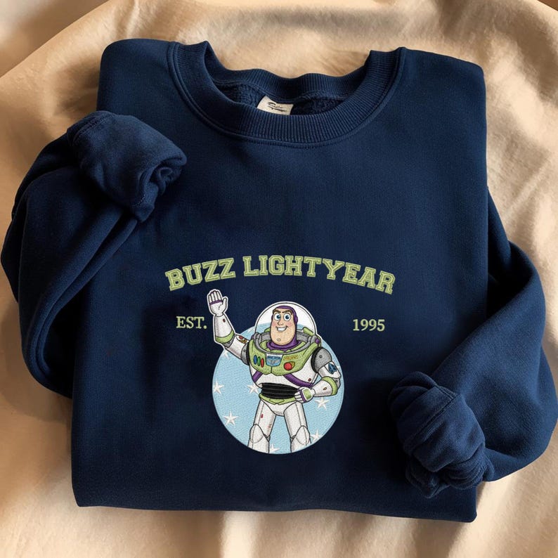 Puede incluir: Sudadera azul marino con un dise&ntilde;o de Buzz Lightyear. El dise&ntilde;o incluye el texto "BUZZ LIGHTYEAR" encima de una ilustraci&oacute;n del personaje, con "EST. 1995" debajo. Tiene cuello redondo y pu&ntilde;os acanalados.