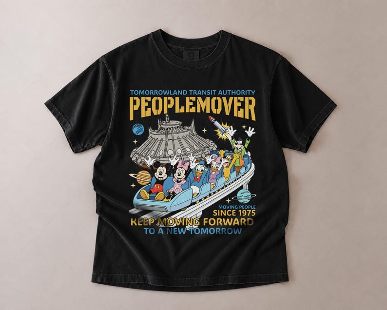 May include: Black t-shirt featuring a colorful graphic of the PeopleMover ride with Mickey Mouse, Minnie Mouse, Donald Duck, and other characters. The shirt includes the text "Tomorrowland Transit Authority PEOPLEMOVER" and "Moving People Since 1975."