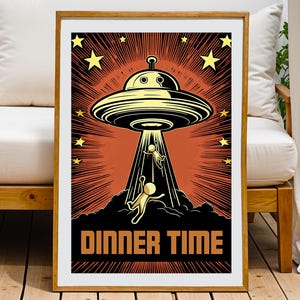 Puede incluir: Un póster enmarcado con una ilustración retro de un OVNI amarillo que secuestra a dos figuras. El fondo es naranja con líneas radiantes y estrellas amarillas. Las palabras "DINNER TIME" están en letras naranjas en negrita.