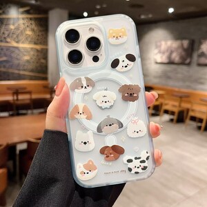 May include: Clear phone case decorated with various cartoon dog illustrations. The case has a light blue border and features a magnetic ring. The phrase "Have a nice day" is printed on the case.
